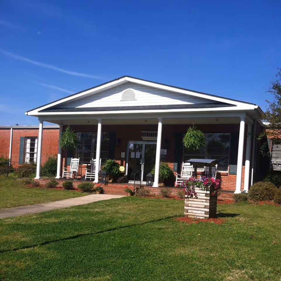 Evergreen Health and Rehabilitation Center front porch with white columns and rocking chairs.