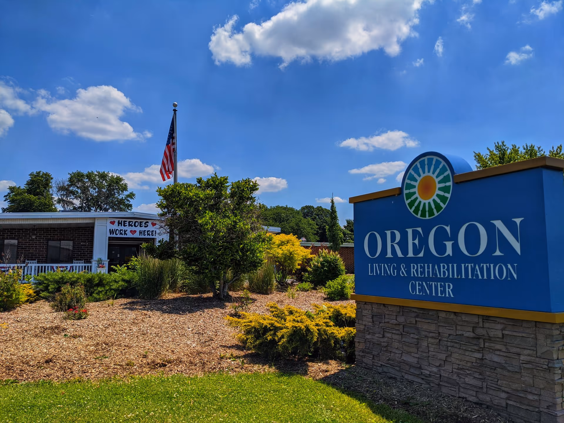 Blue Oregon Living & Rehabilitation Center sign with landscaping and a building in background.