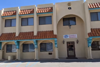 Facade of Comfort Keepers facility in Las Cruces, NM, with arched entrance and signage.