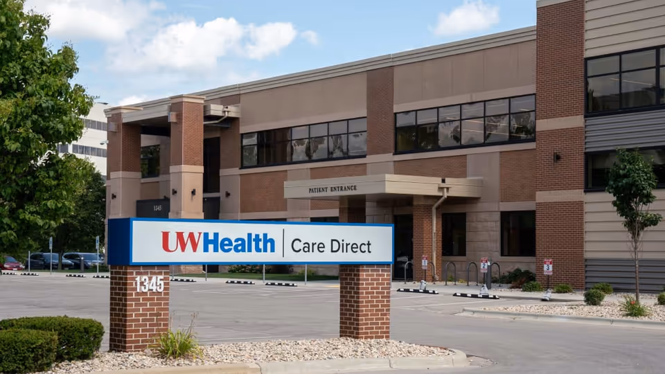 Exterior view of UW Health Care Direct building with entrance sign and parking lot.