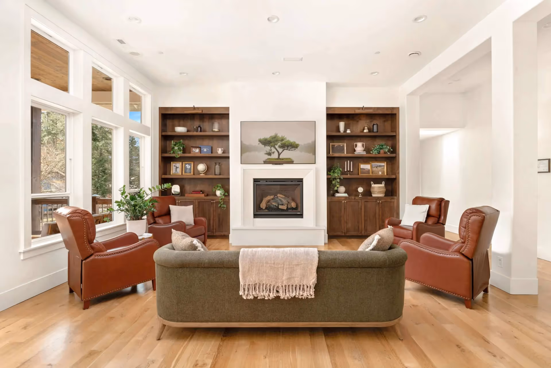 Bright senior living facility living room with fireplace, built-in shelves, and leather chairs.