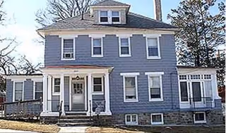 Blue two-story assisted living building with front porch, windows, and sunroom extension.