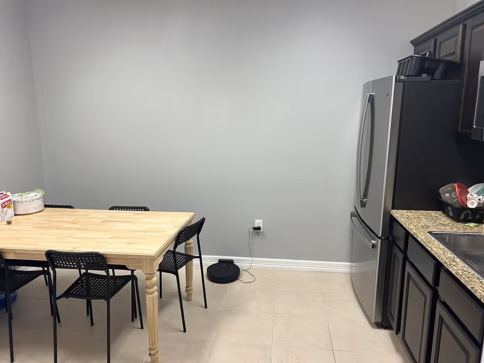 Small kitchen/dining area with a wooden table, black chairs, and stainless appliances.