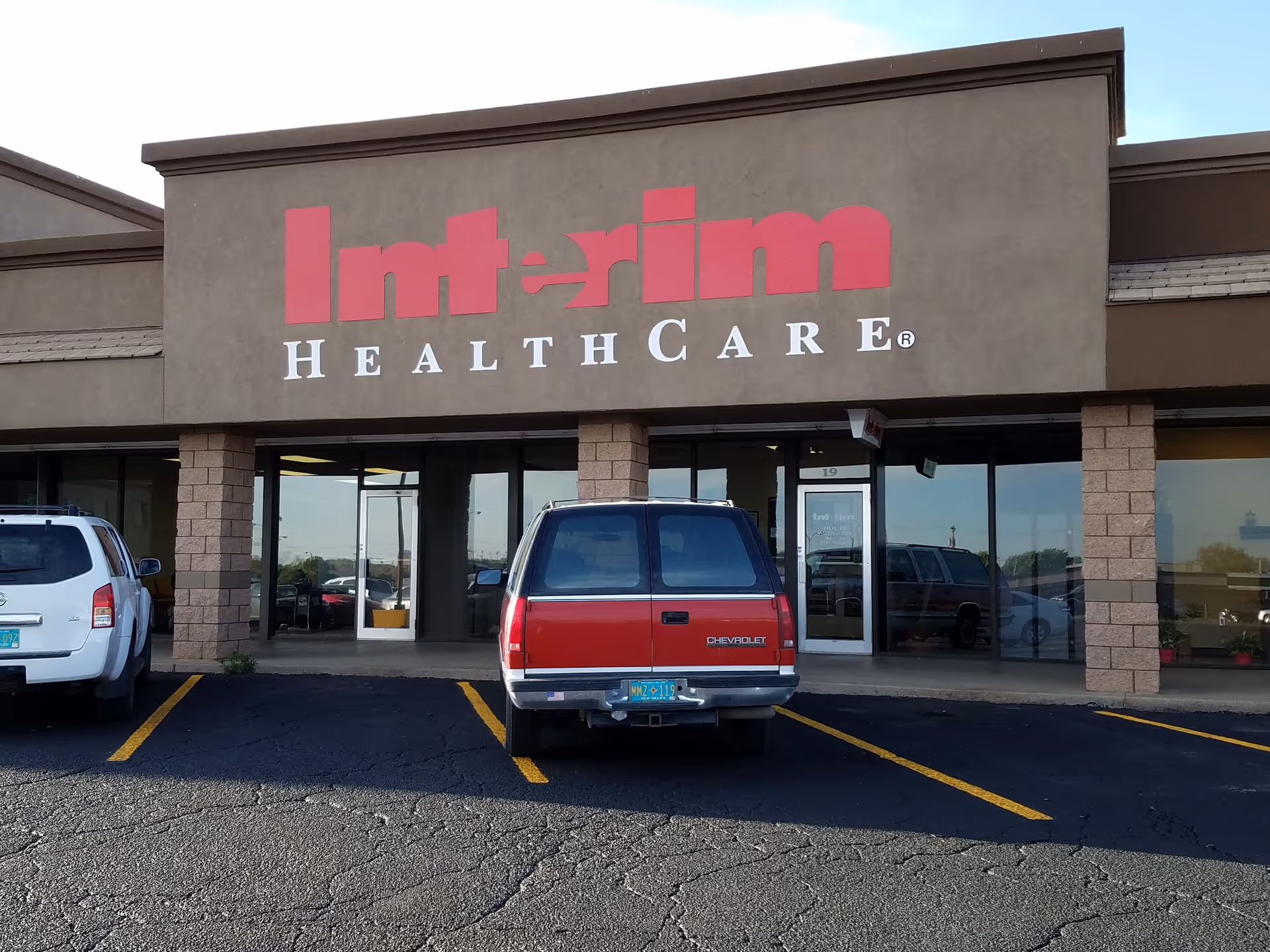 Front exterior of Interim HealthCare building with parked vehicles in the lot.