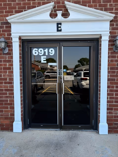Double glass doors in a brick facade with a white frame and an E above.