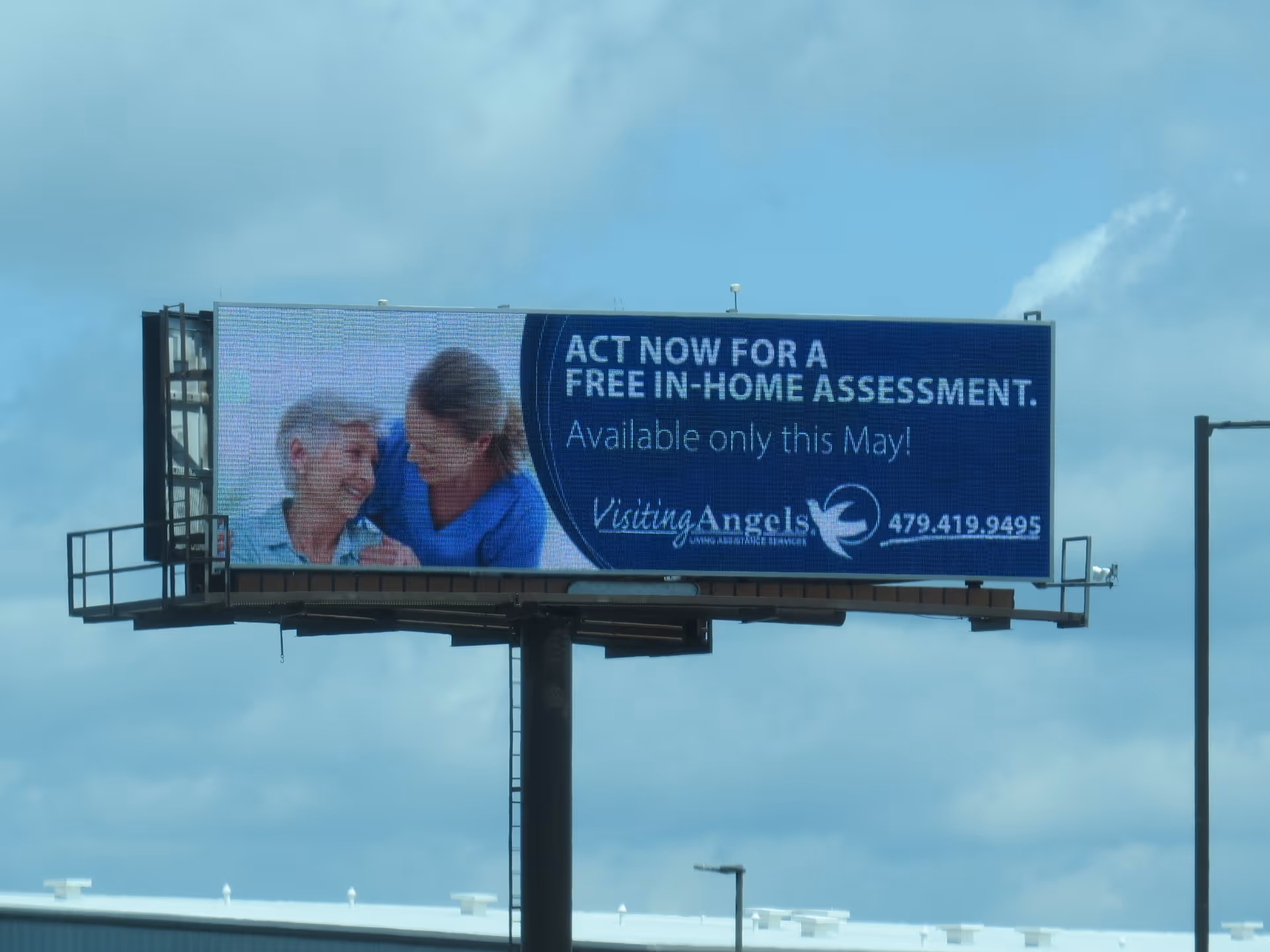 Outdoor billboard features two people—a caregiver and elderly patient—promoting Visiting Angels.