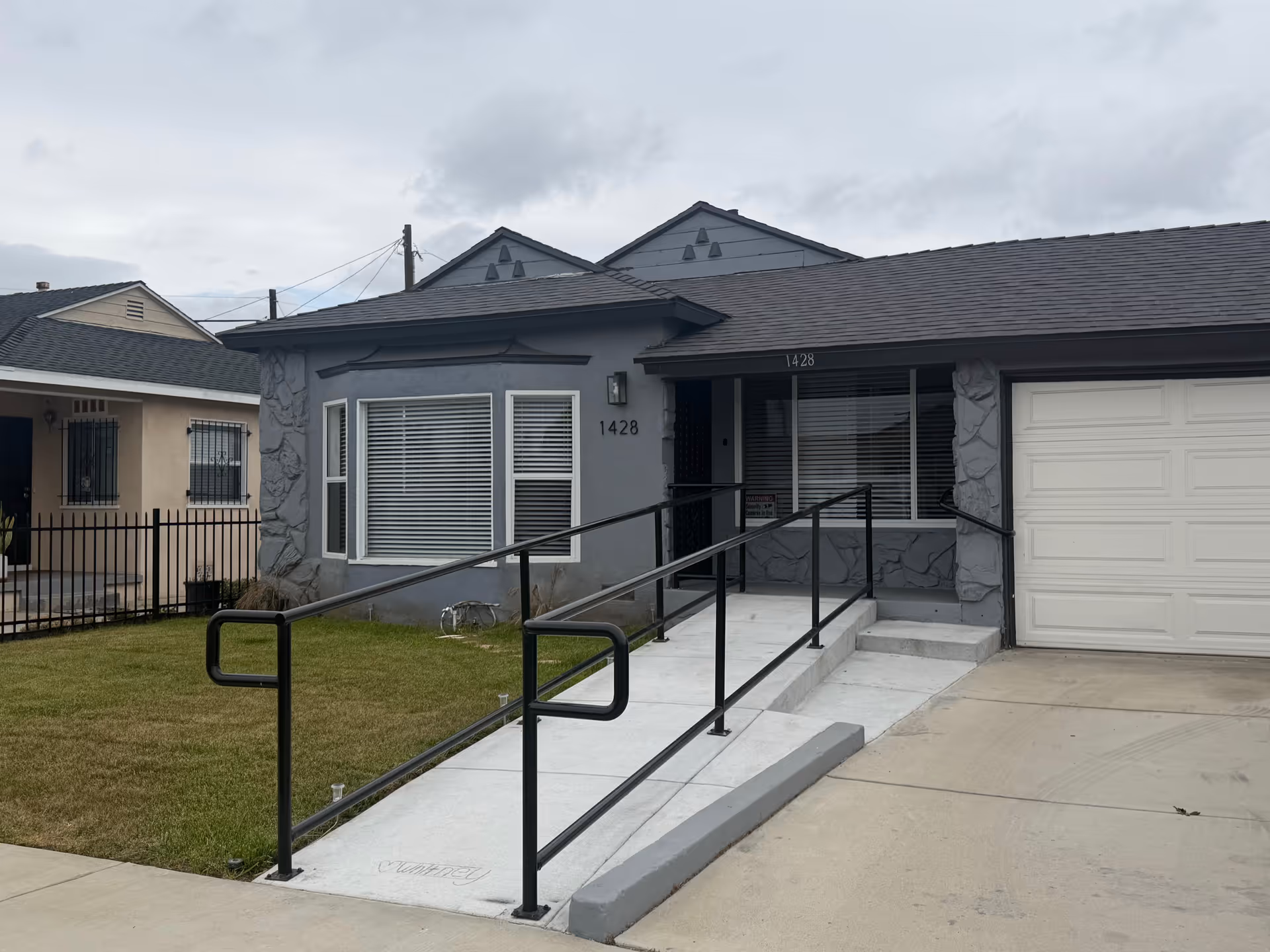 Front exterior of a single-story gray building with a wheelchair ramp and attached garage.