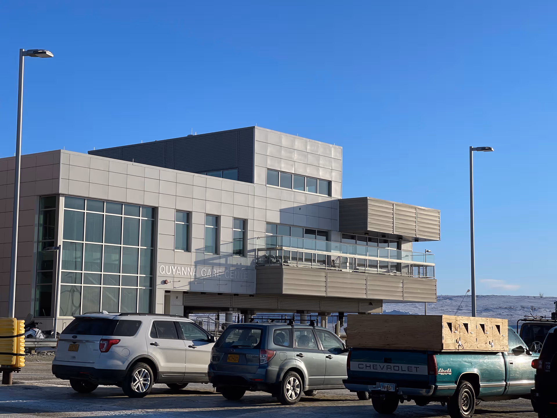 Quyanna Care Center exterior with glass facade and parked cars beneath a clear sky