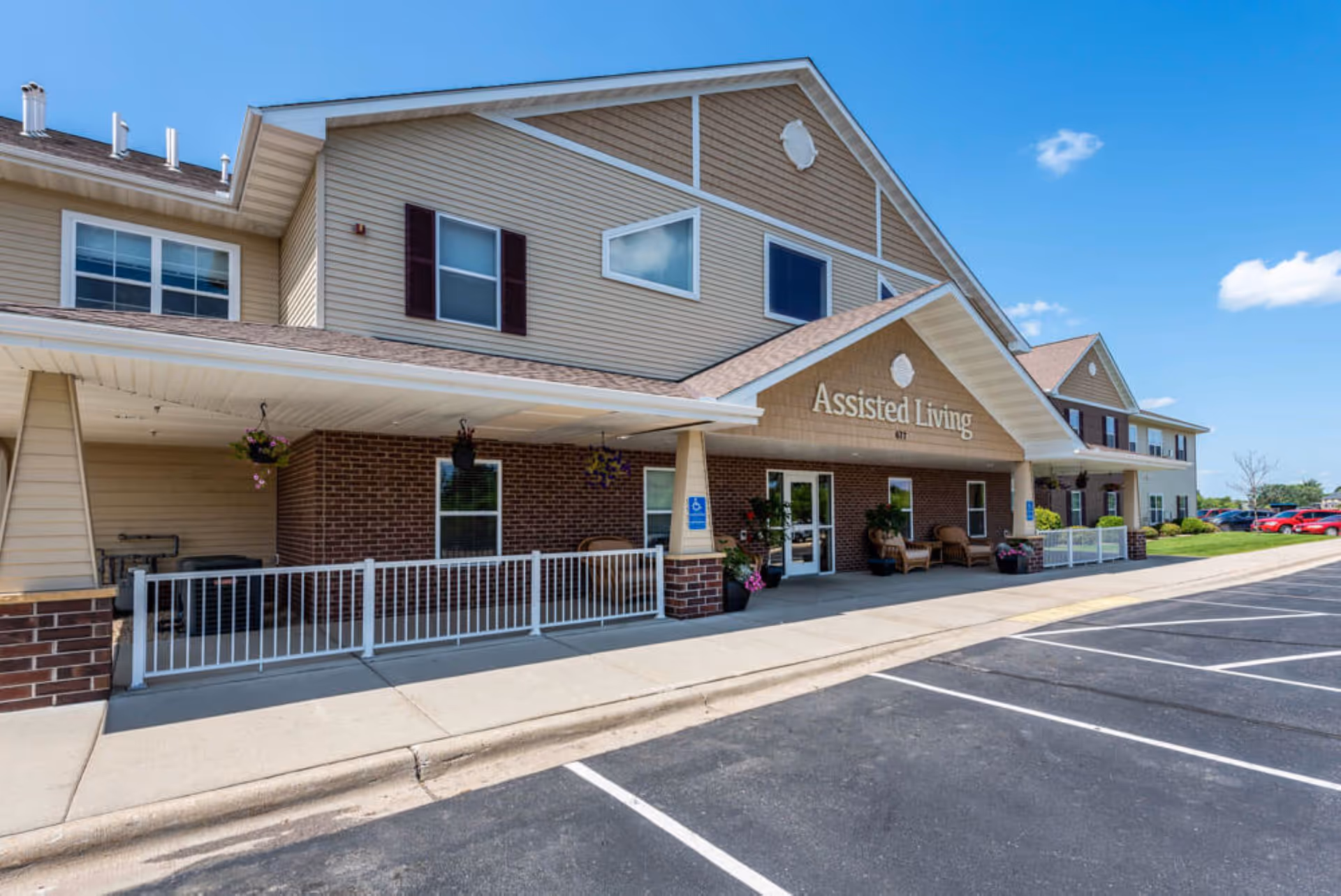 Exterior view of Edgewood Sartell Assisted Living building with entrance, porch seating, and parking.