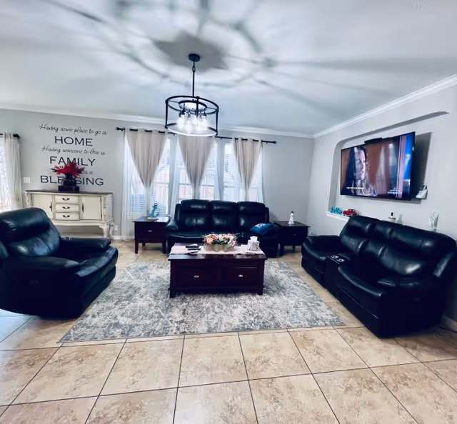 Cozy Safe Harbor living room with black leather sofas, coffee table, rug, and wall-mounted TV.