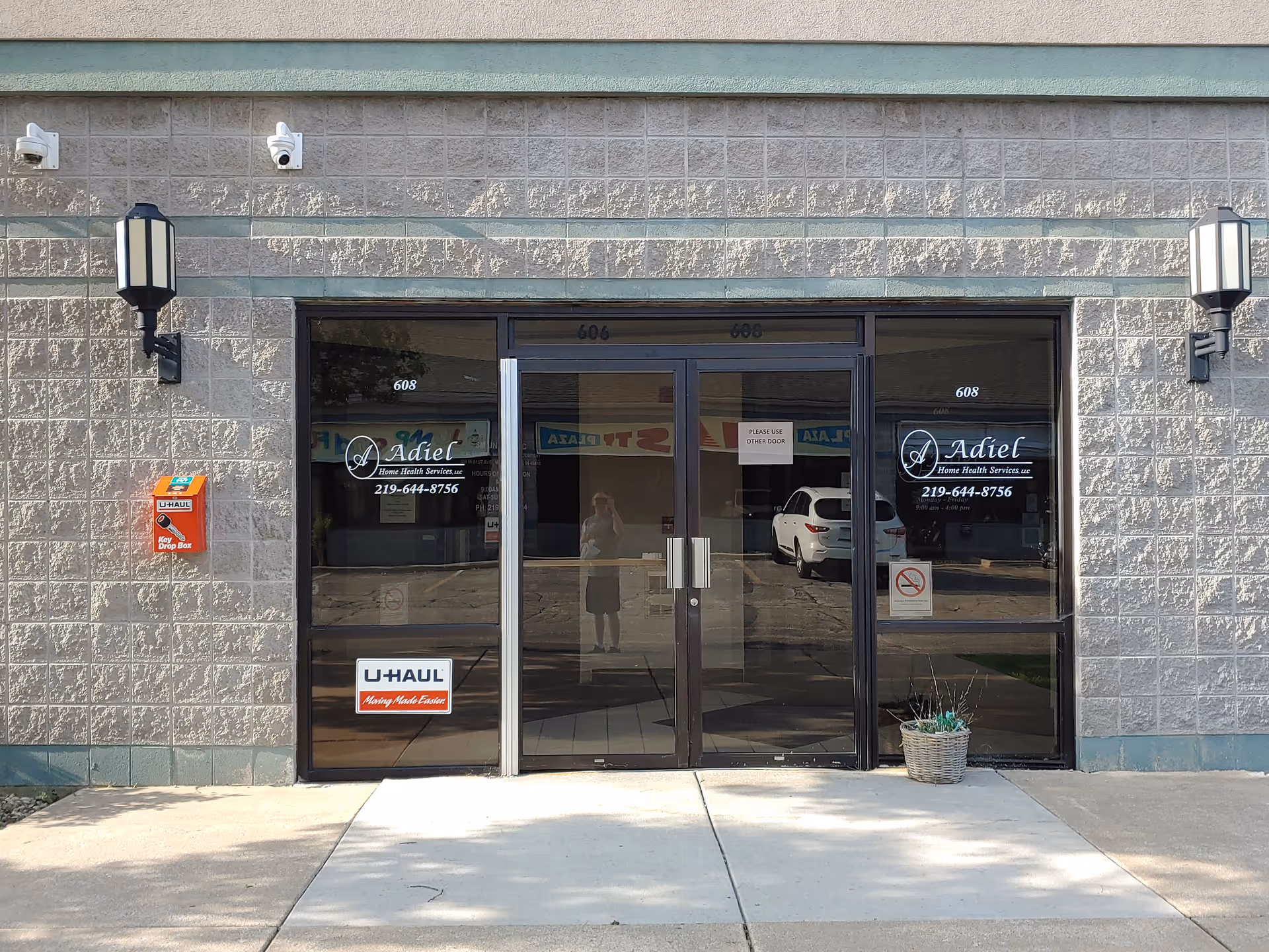 Exterior entrance of Adiel facility with glass doors, signage, and wall lanterns.
