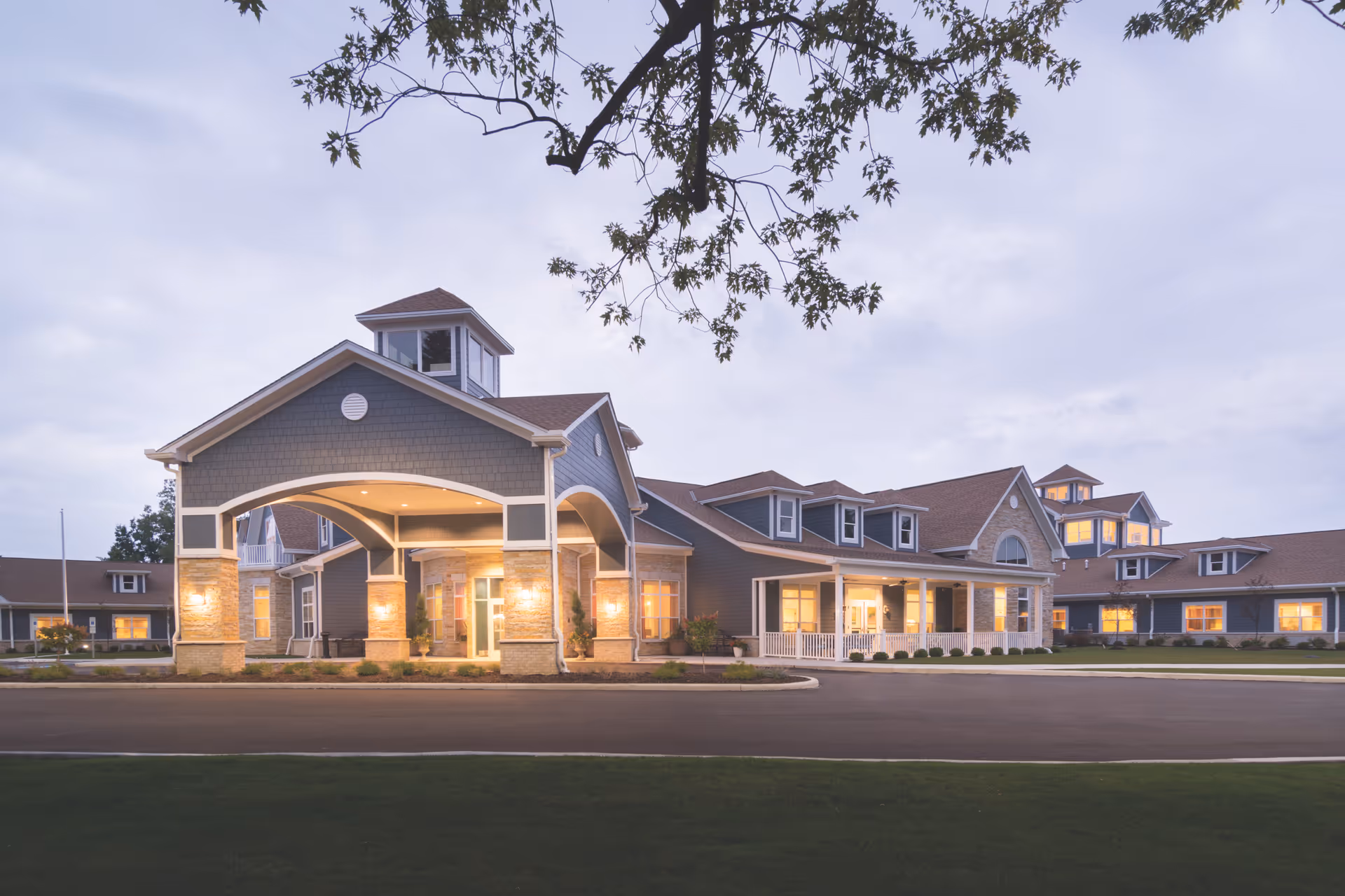 Exterior of a senior living facility with a covered entrance and warmly lit windows.