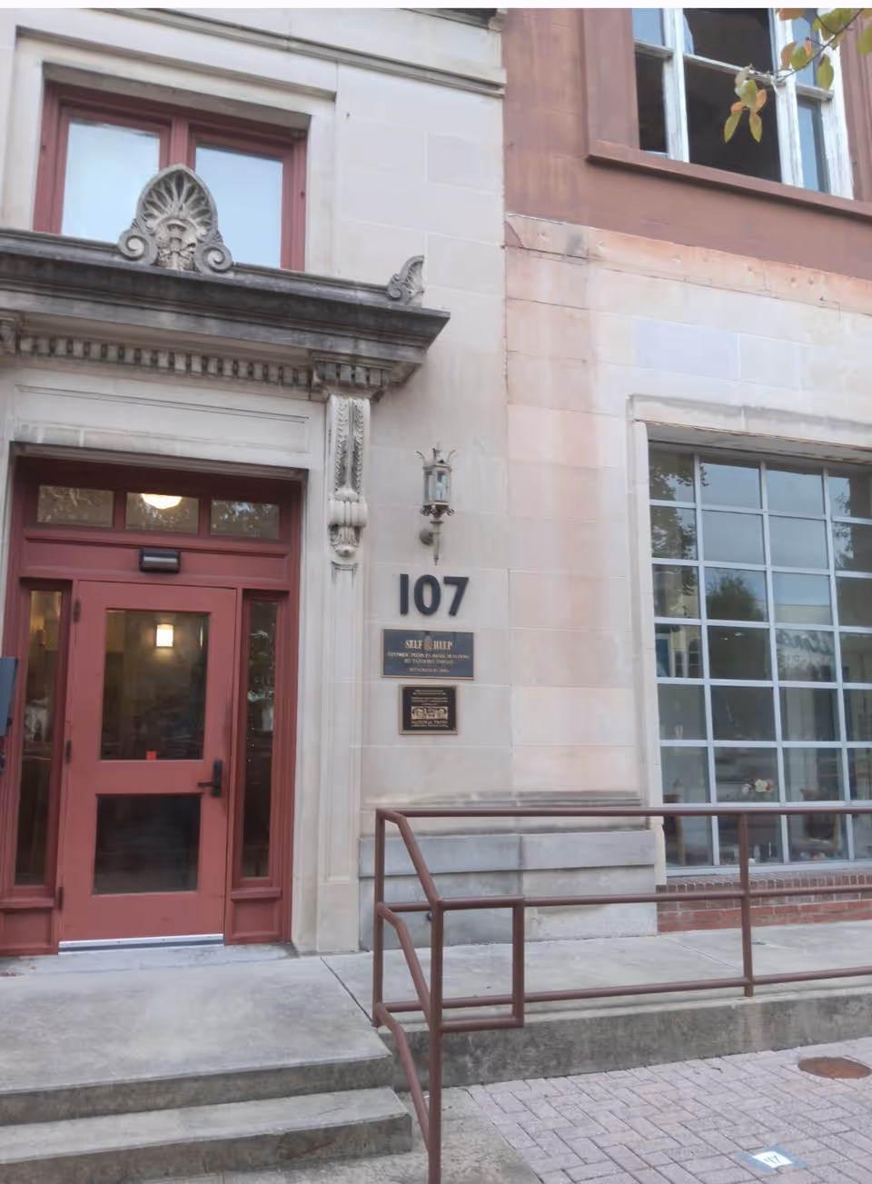 Front entrance of a stone building with red door and the number 107