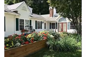 Front exterior of Cedar Hill Health Care with a colorful flower bed and greenery