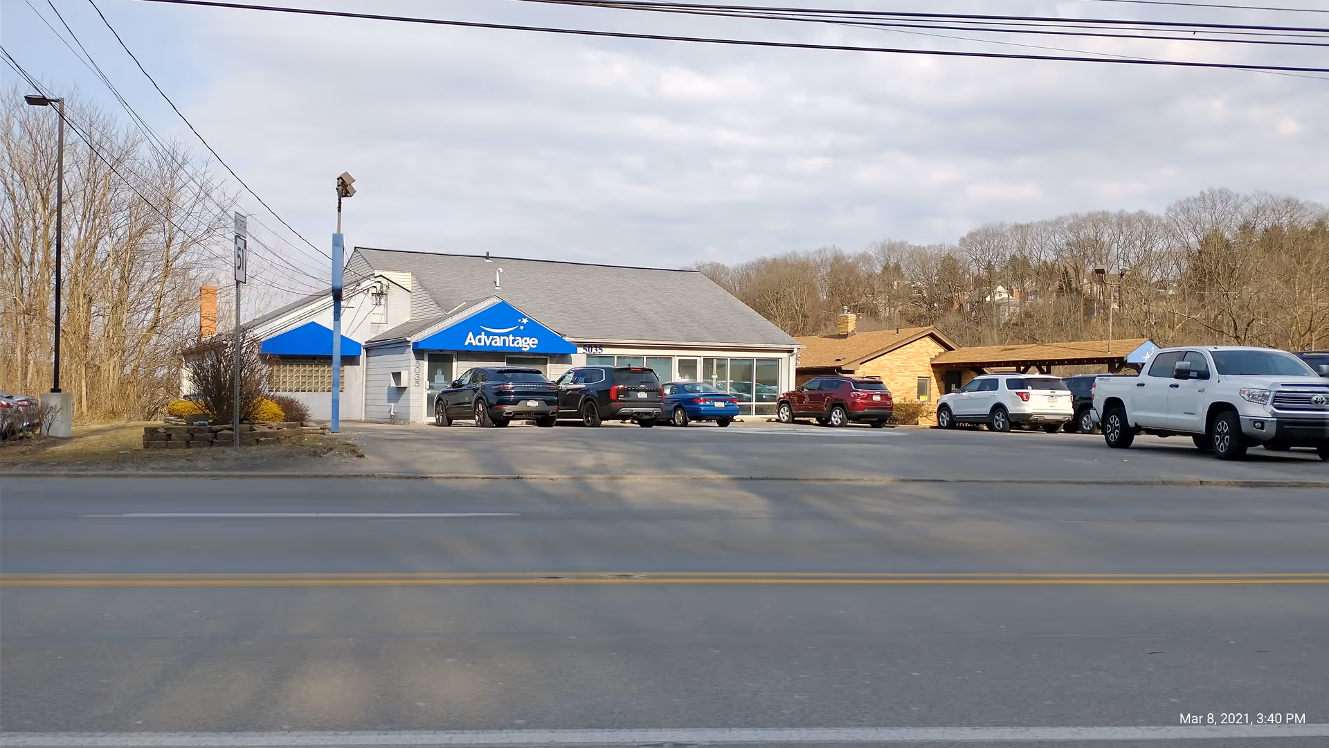 Exterior view of the Advantage building with a blue awning and parked cars along the street.