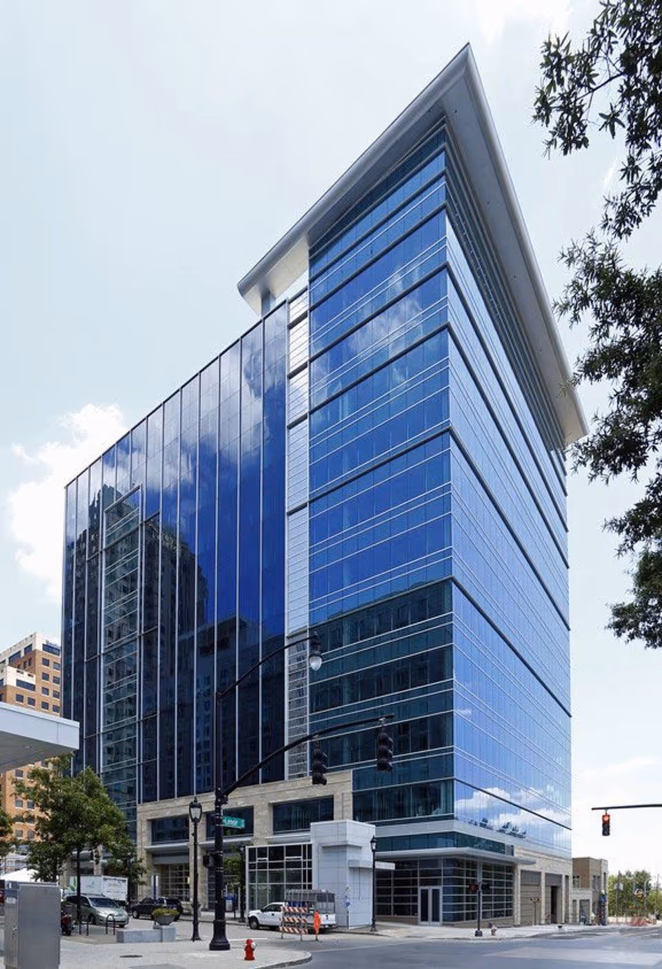 A modern glass-clad high-rise building along a city street.