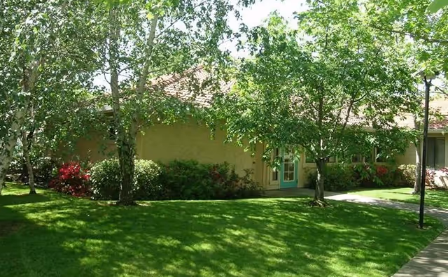 Exterior view of Creekside Village Apts entrance with trees, lawn, and pathway
