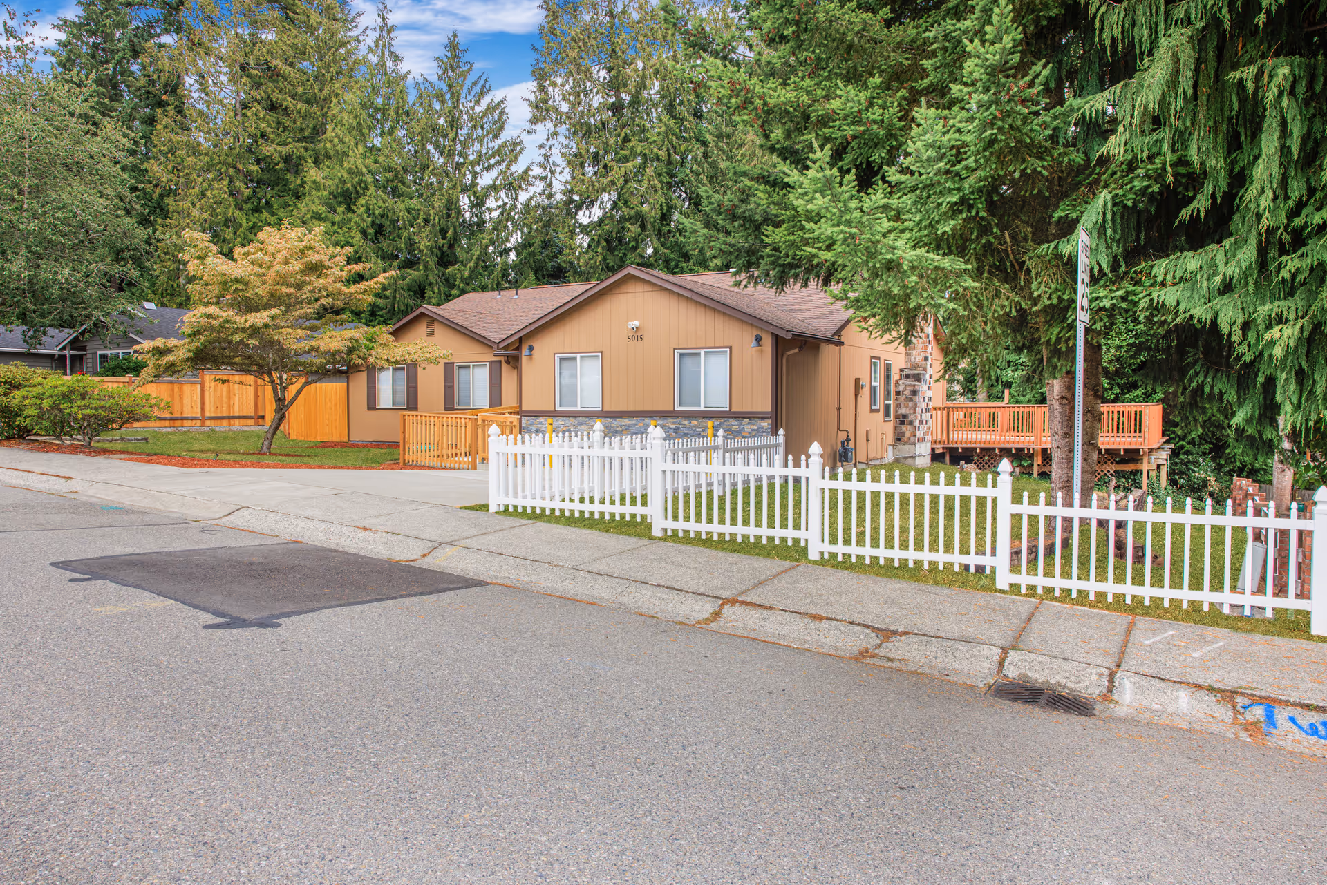 Front view of Penny Creek Adult Family Home with white picket fence and trees.