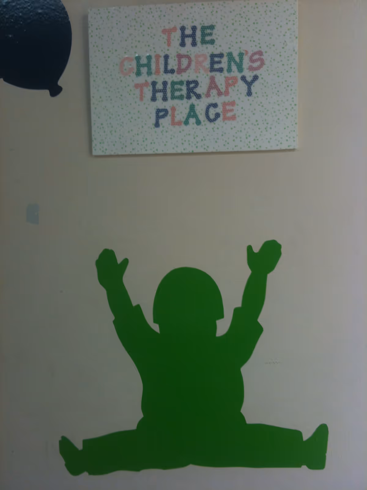 Interior wall with a sign reading The Children's Therapy Place and a green silhouette mural.