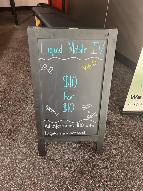 A chalkboard sign advertising Liquid Mobile IV in a hallway of a facility.