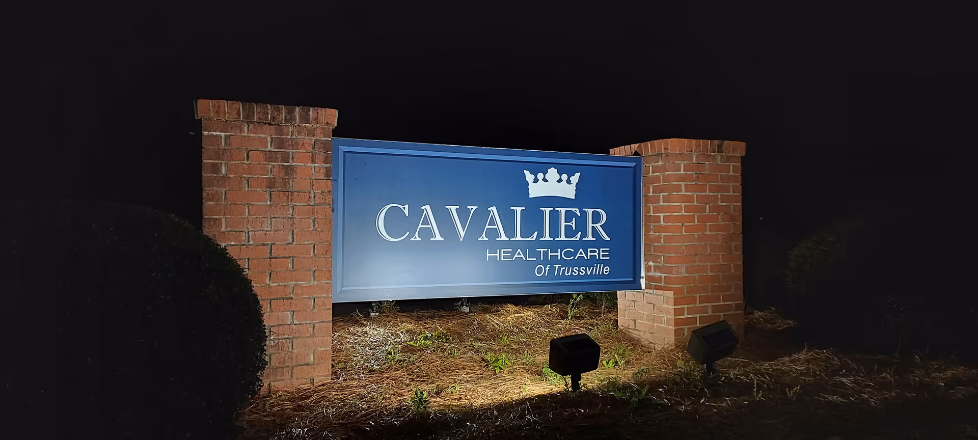 Nighttime view of Cavalier Healthcare sign between brick pillars