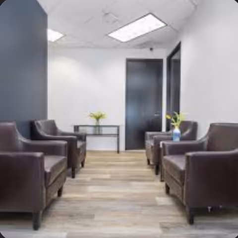 A modern lounge area with brown armchairs and a small table in a senior living facility.