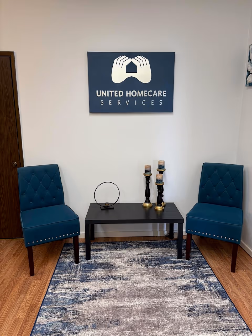 Two teal chairs flank a black table with candles beneath a United Homecare Services sign.