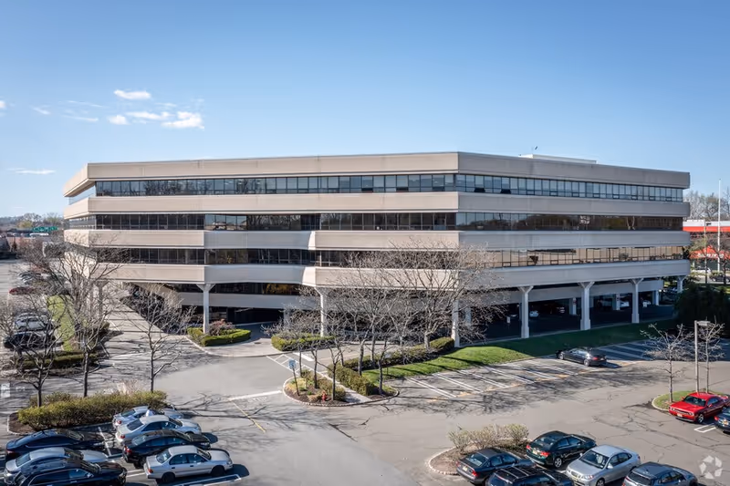Exterior view of a modern, multi-story senior care facility with a surrounding parking lot.