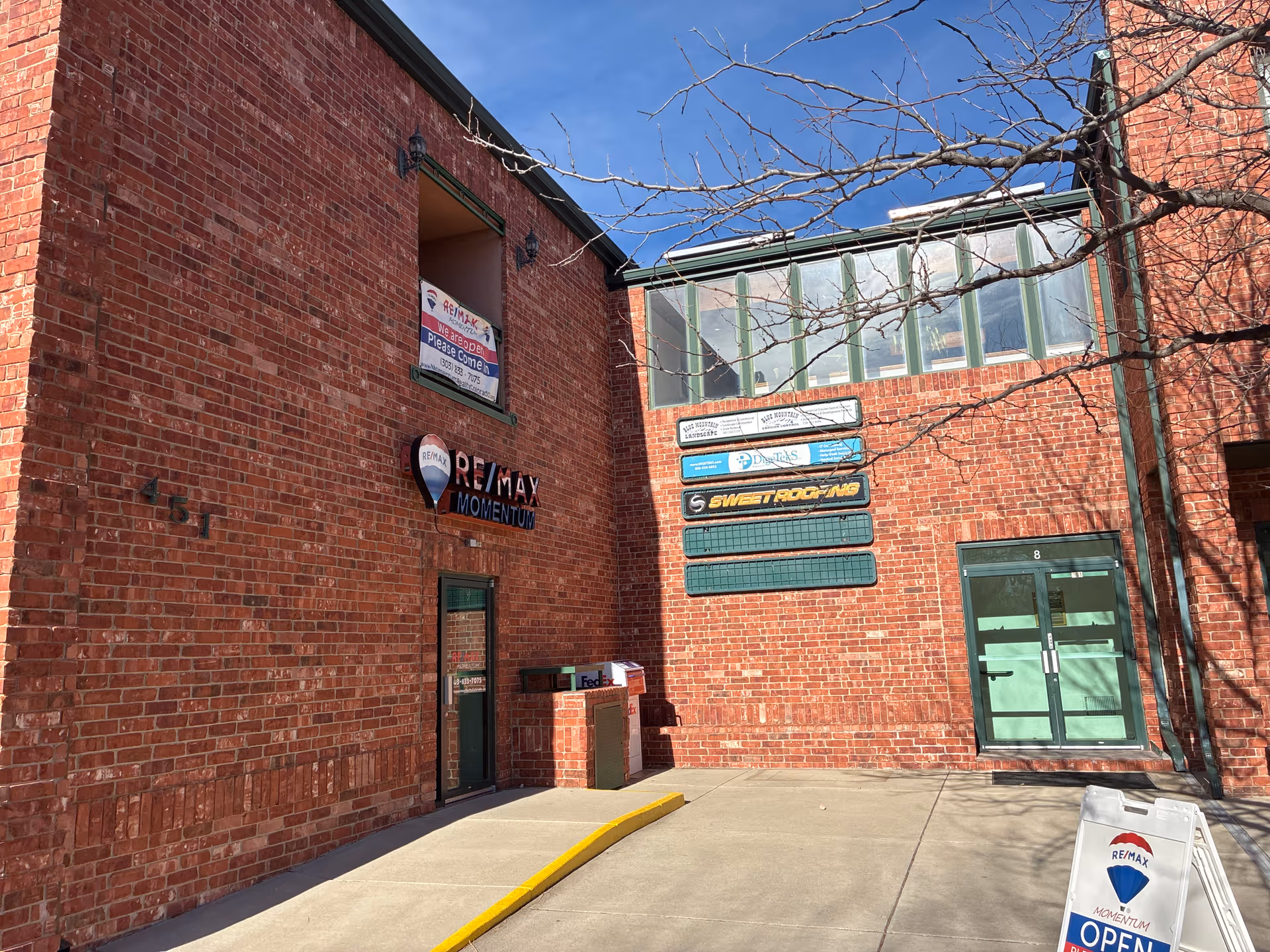 Brick storefront with signs and glass doors on a sunny exterior.