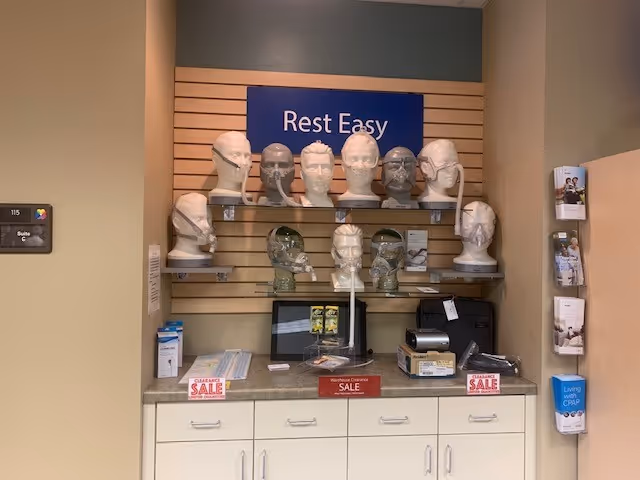 Display of mannequin heads wearing masks on shelves under Rest Easy sign.