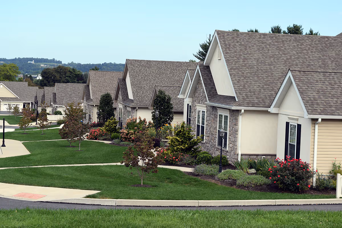 Row of single-story ranch-style residences with landscaped front yards and sidewalks in a retirement community.