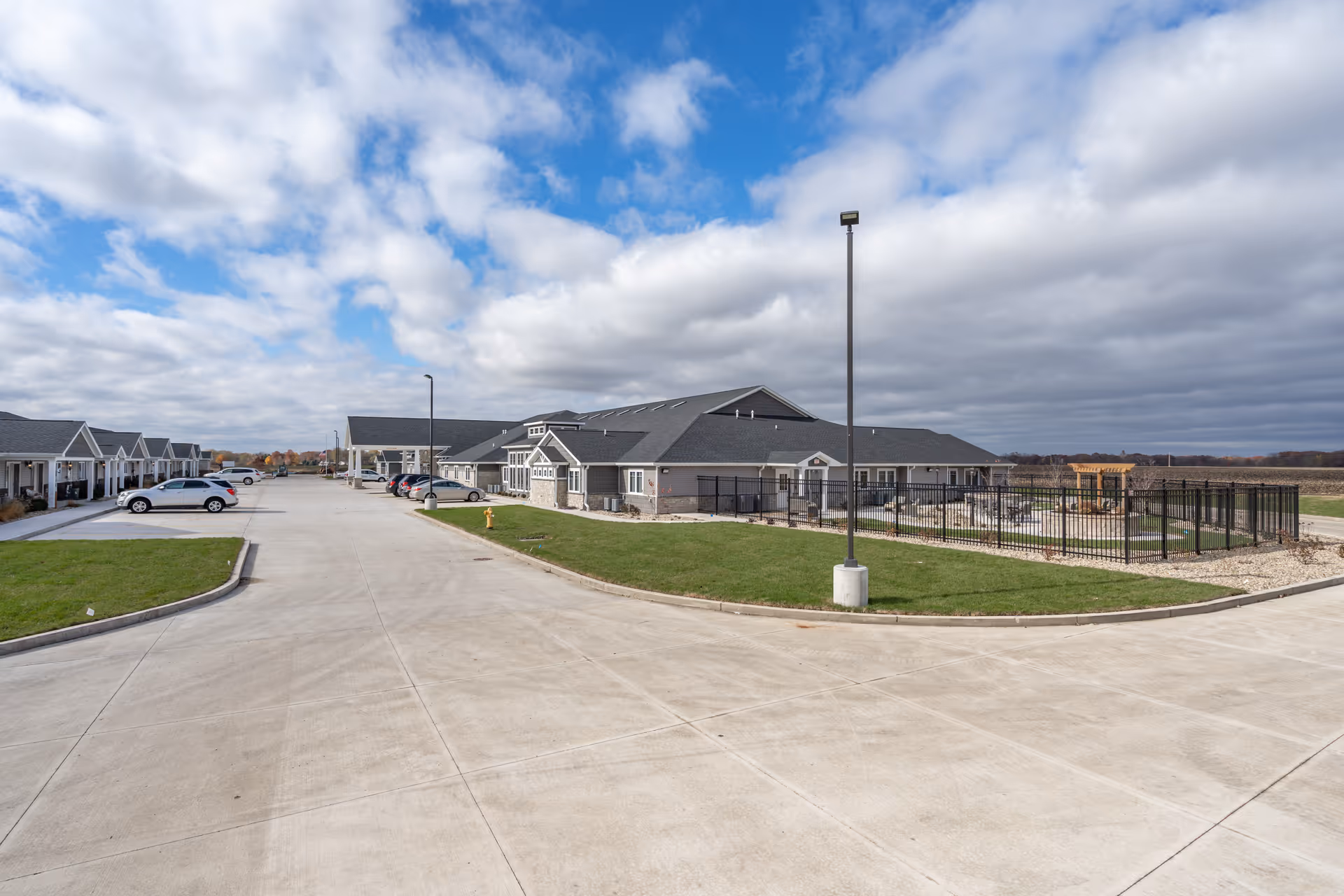 Wide exterior view of Reflections Memory Care Morton campus with parking and fenced outdoor area.