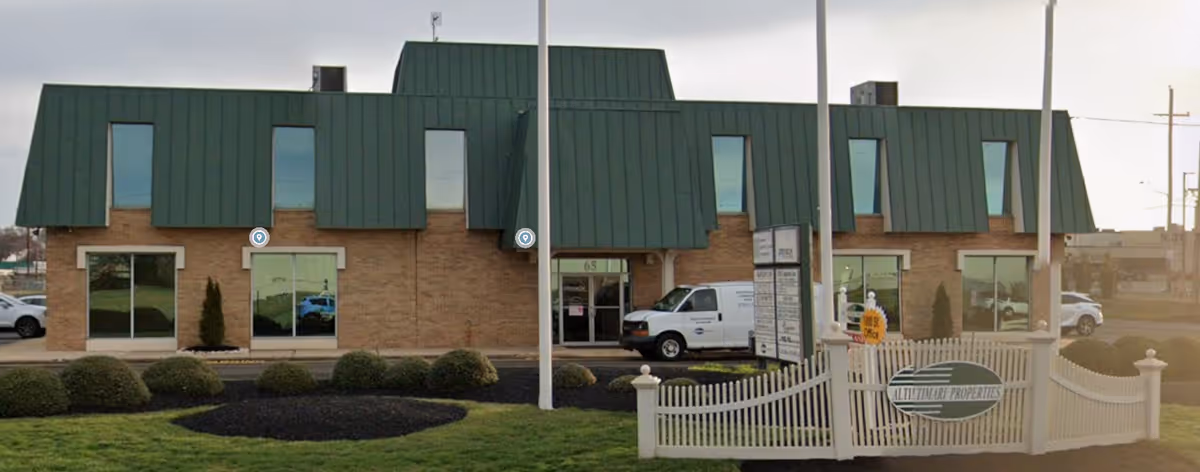Front exterior of CareBuilders At Home facility: brick building, green metal roof, white gate