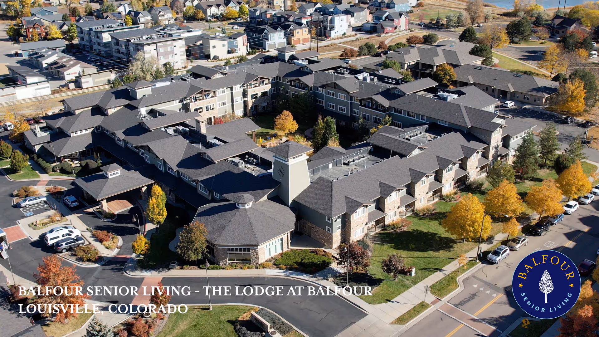 Aerial view of Balfour Senior Living - The Lodge at Balfour in Louisville, Colorado, showing a large senior living facility with multiple connected buildings, parking areas, and surrounding trees with autumn foliage.