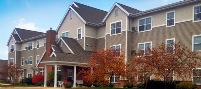 Exterior view of Charter Senior Living of Verona, a multi-story beige building with a red-brick entrance.