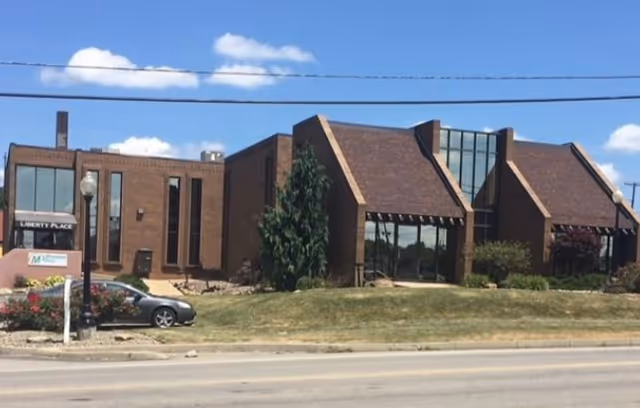 Exterior view of a brick senior living facility with a glass front entrance.