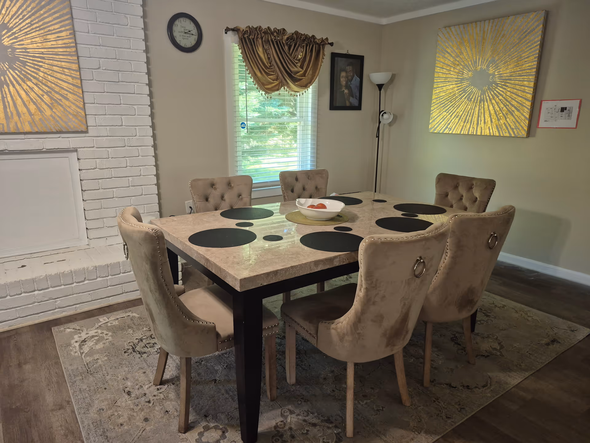 Beige tufted chairs surround a marble dining table in a bright dining room.
