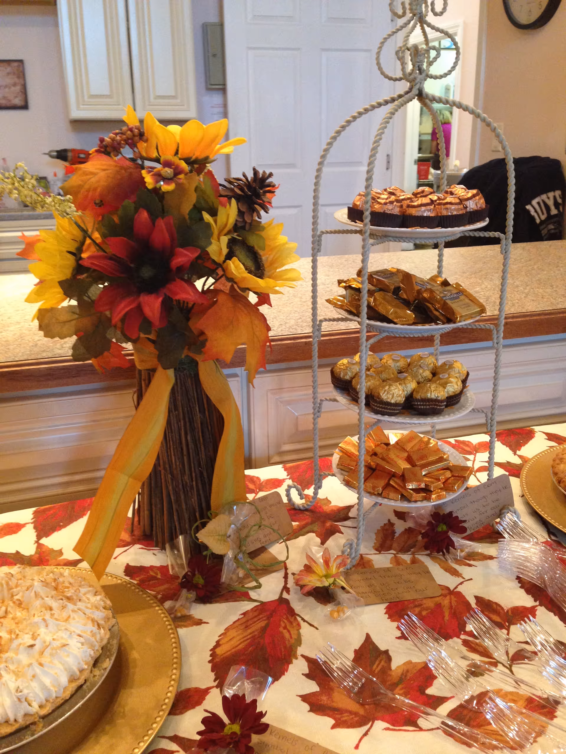 Autumn bouquet and tiered pastry stand decorate a dining table in a kitchen area.