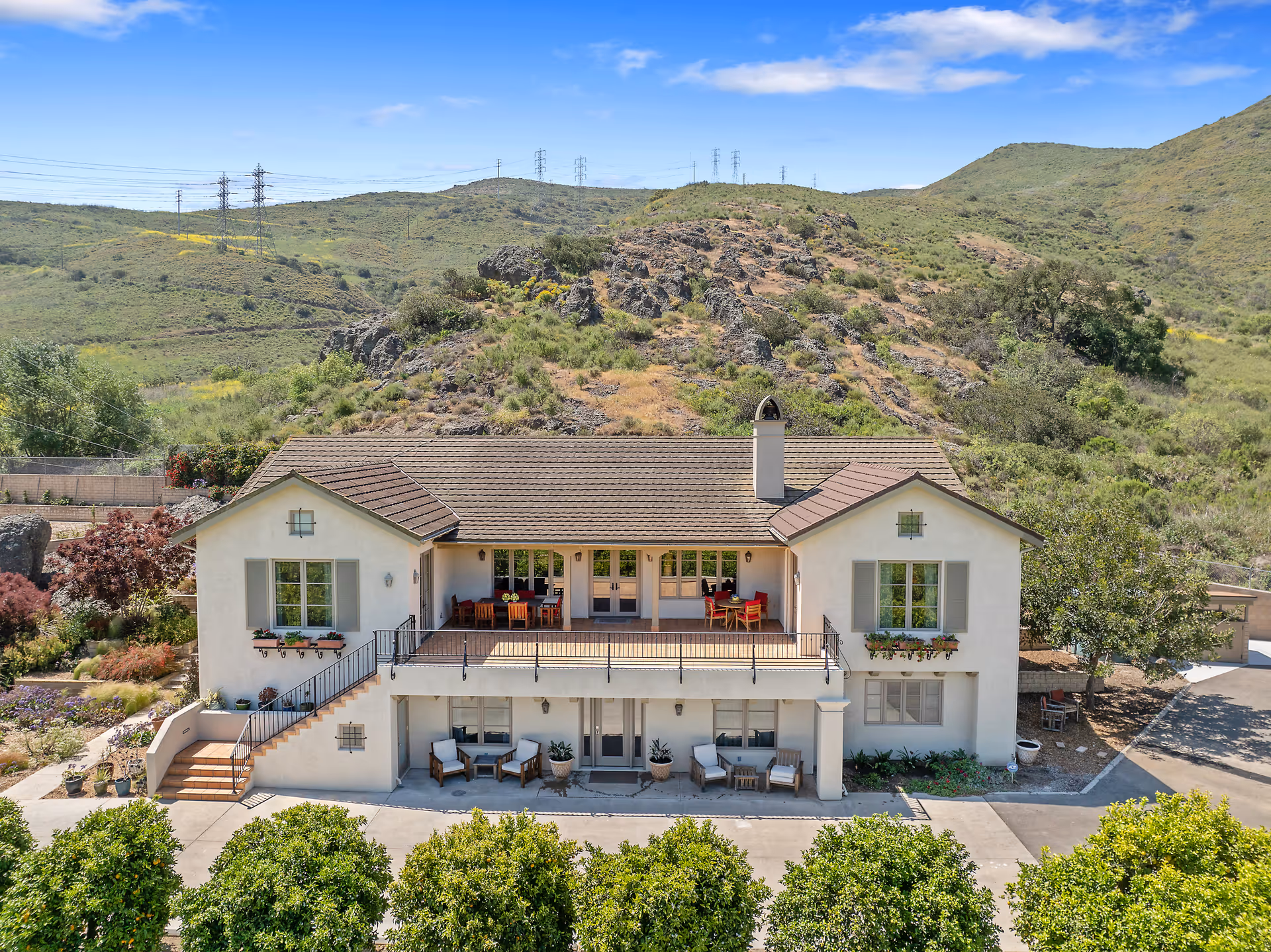 Two-story senior living facility with outdoor seating on balconies and a hillside backdrop.