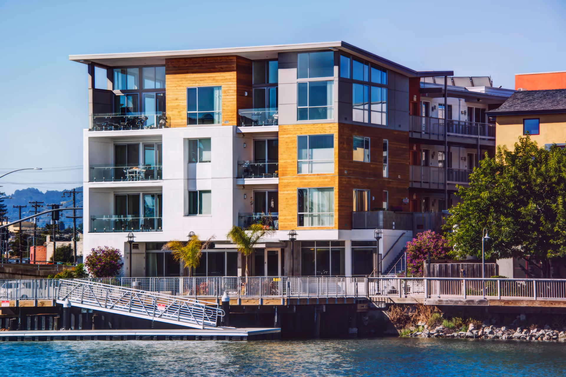 Modern multi-story waterfront senior living building with balconies and a dock.