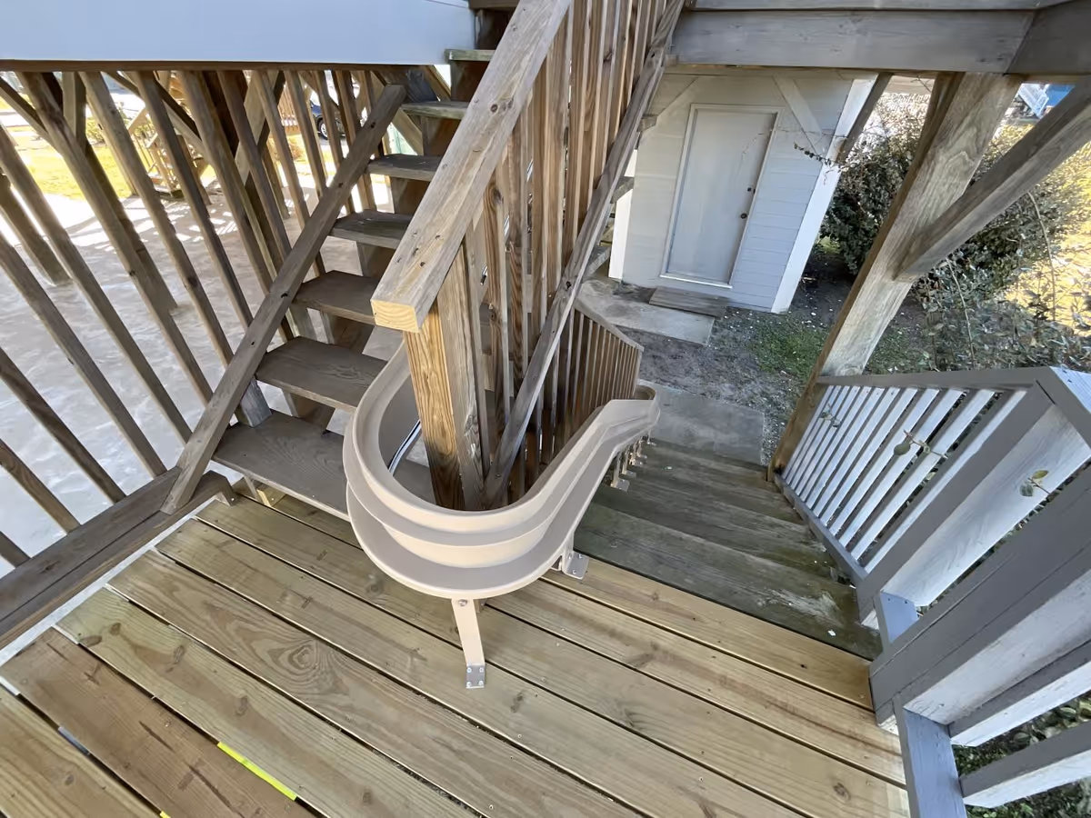 Overhead view of a wooden exterior staircase with railings beside a small shed.