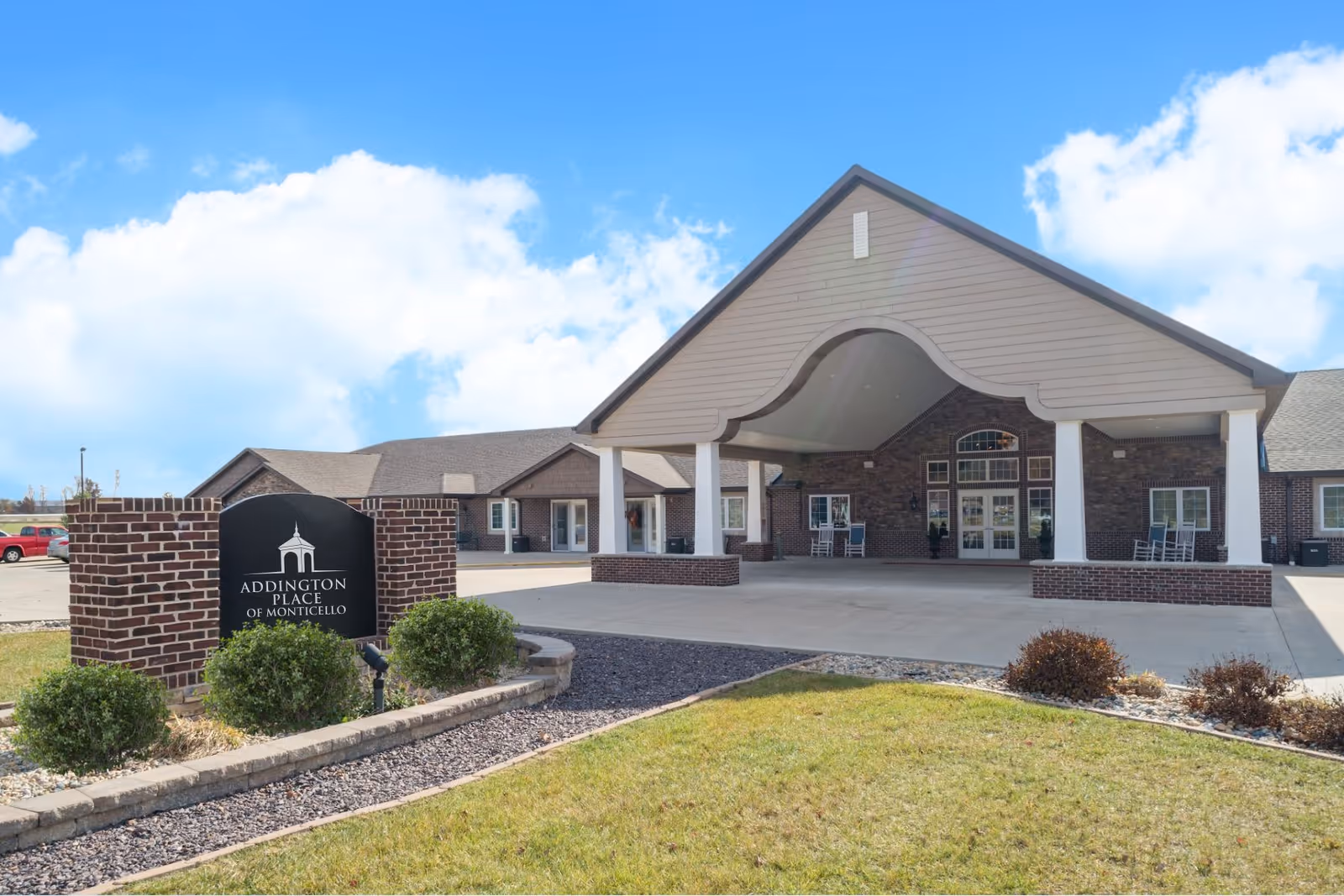 Front exterior of a senior living facility with brick entrance and a sign.