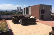 Rooftop terrace with outdoor seating, planters, and a distant city skyline.