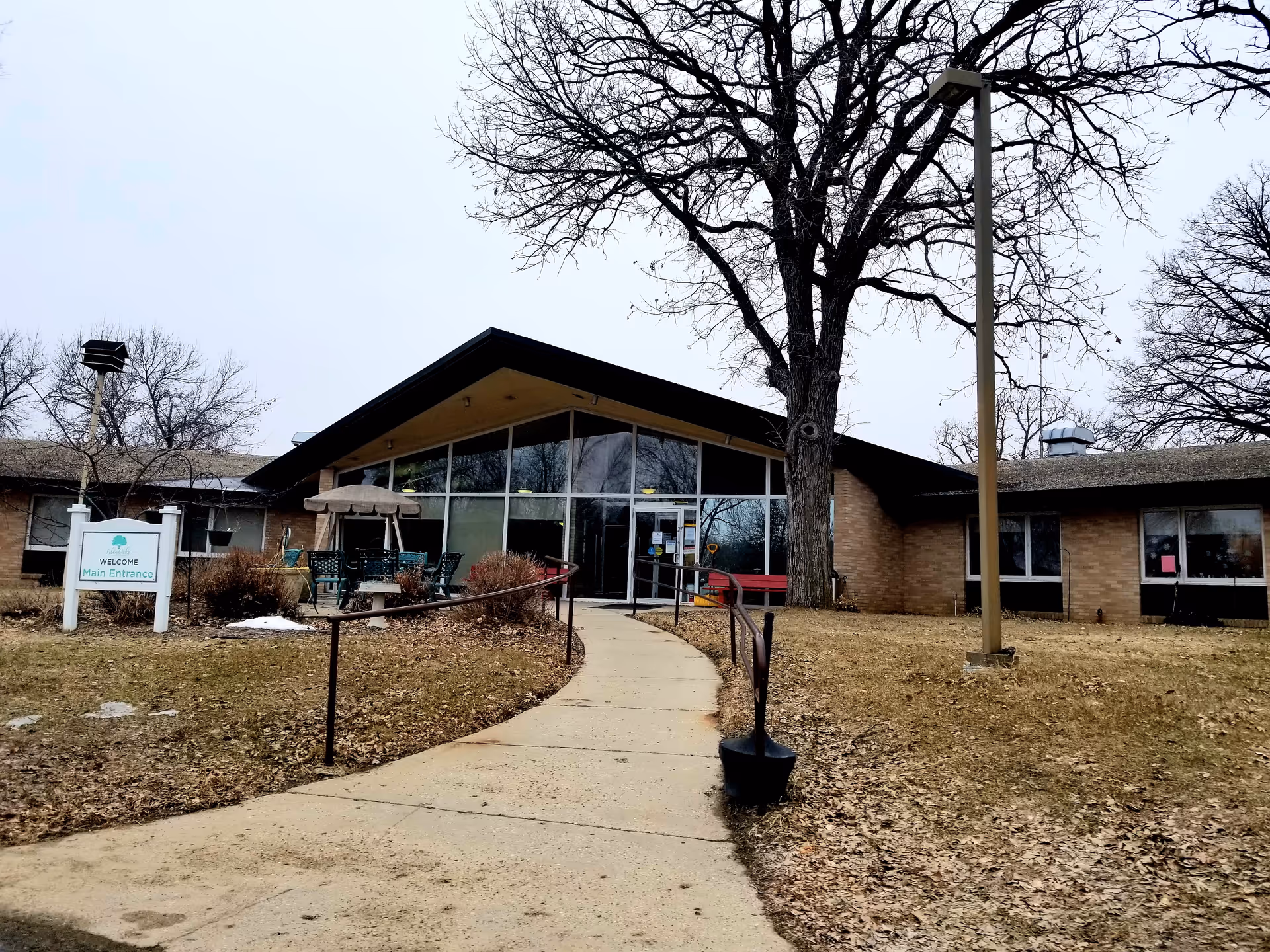 Front entrance of Glenoaks Senior Living Campus with glass doors and a walkway.