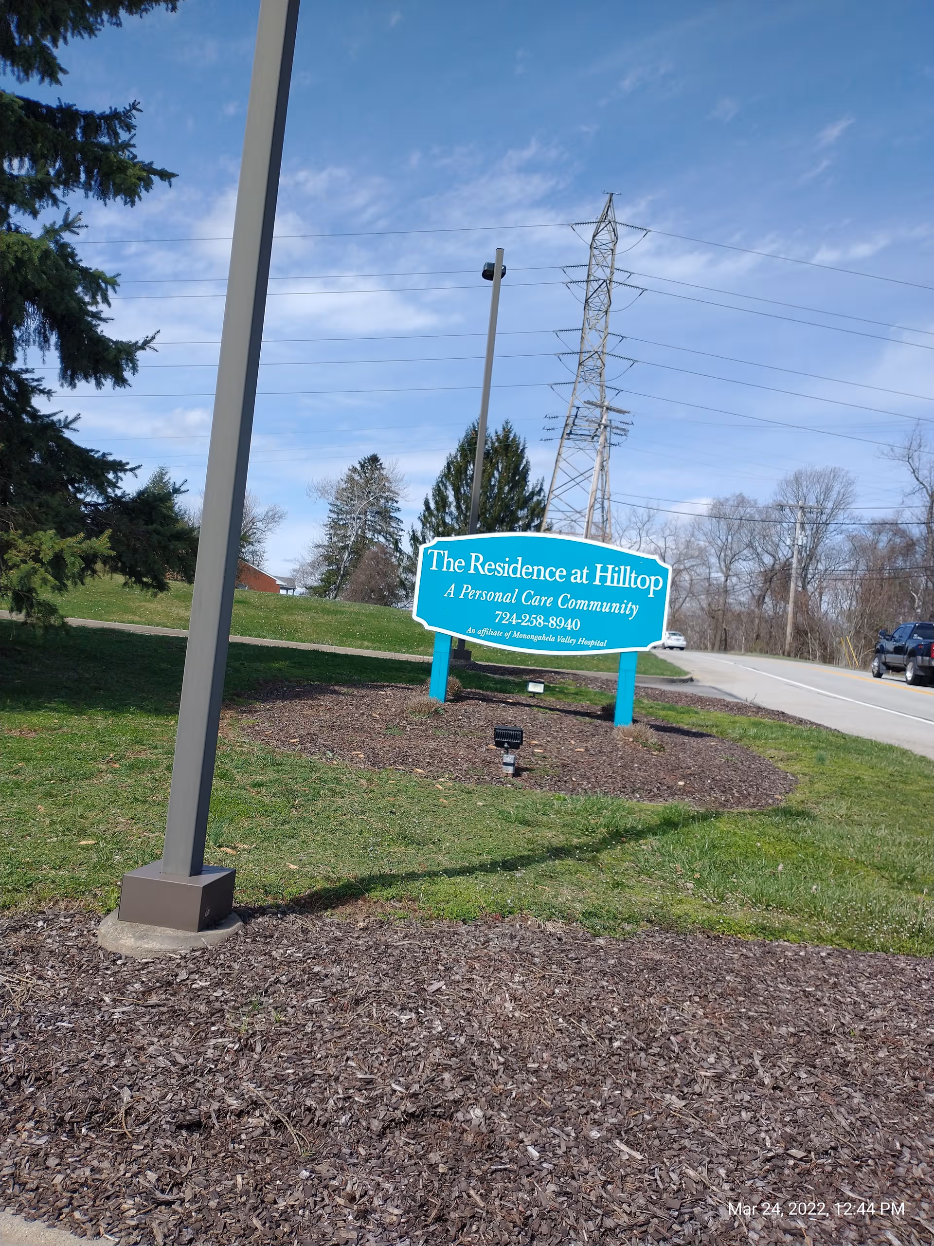 Turquoise sign for The Residence at Hilltop on a landscaped front lawn.