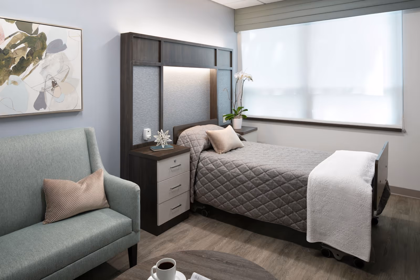 Modern senior living bedroom with a bed, nightstands, a sofa, and a large window.
