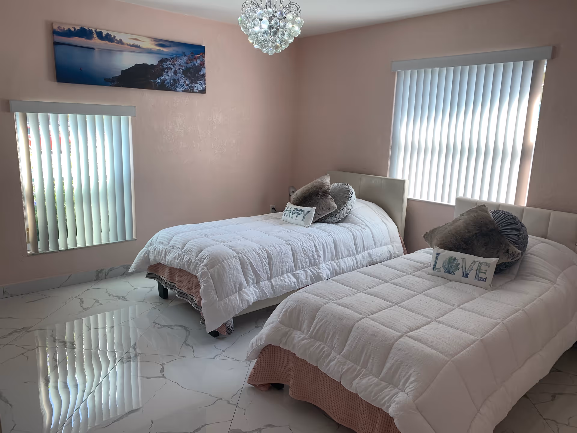 Two single beds with white quilts in a pastel pink bedroom.