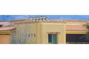 Yellow stucco building front of a senior living facility with a red-tiled roof and blue sky.
