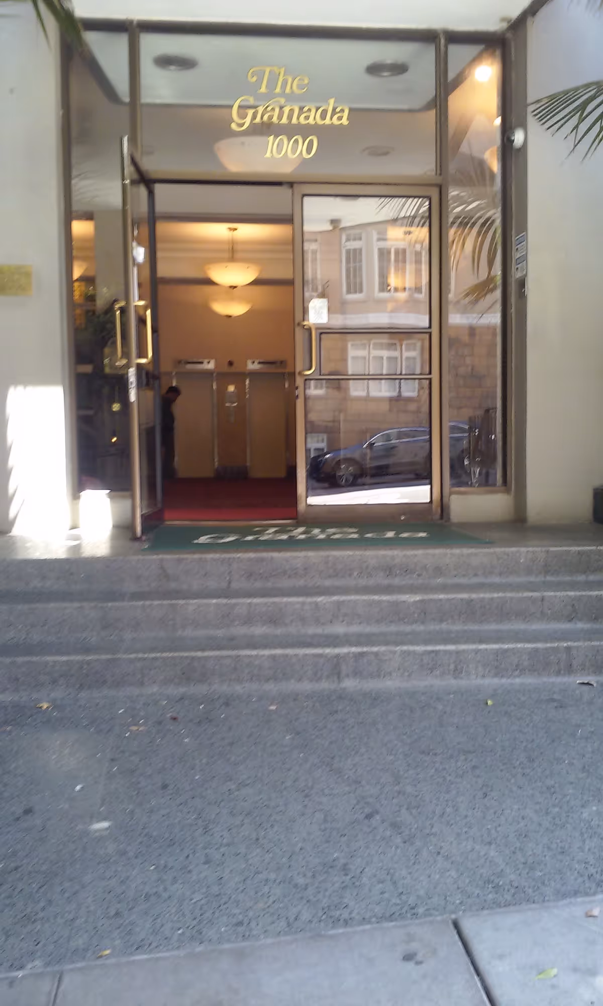Entrance to The Granada 1000 senior living, glass doors, steps, and a lobby visible.