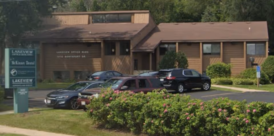Brown, single-story building with a parking lot and landscaped shrubs in front.
